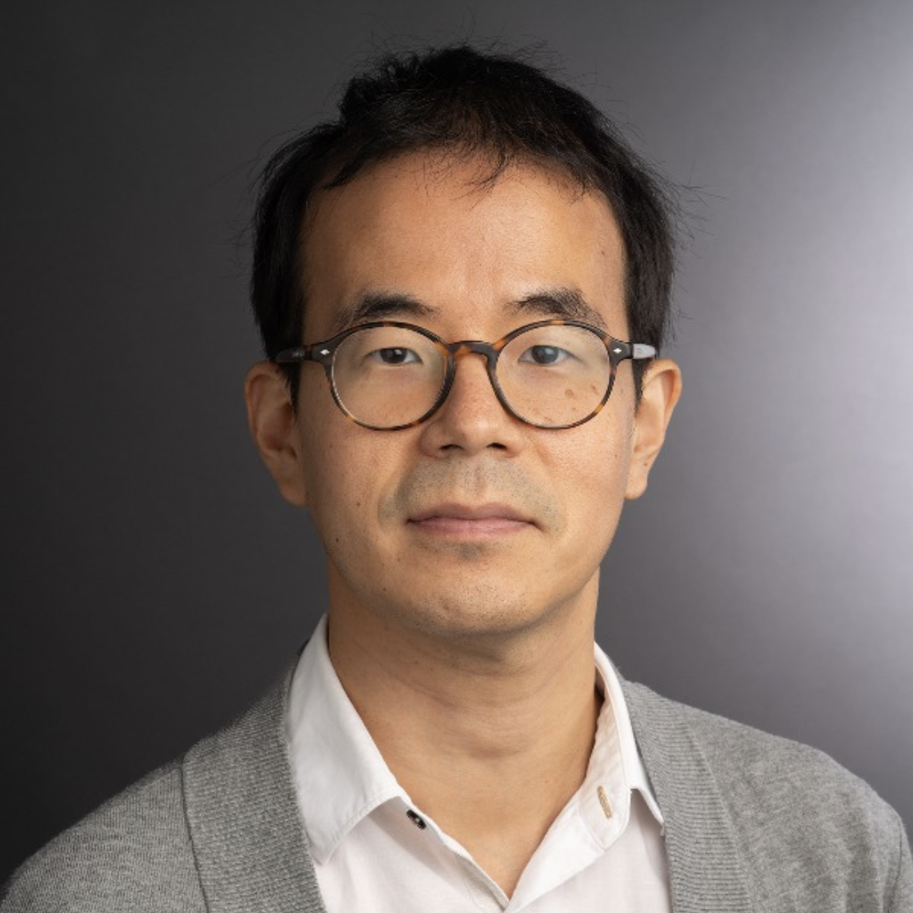 A smiling man with short black hair wearing a white shirt.